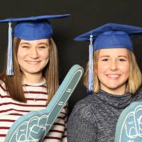 two friends in graduation caps with foam fingers